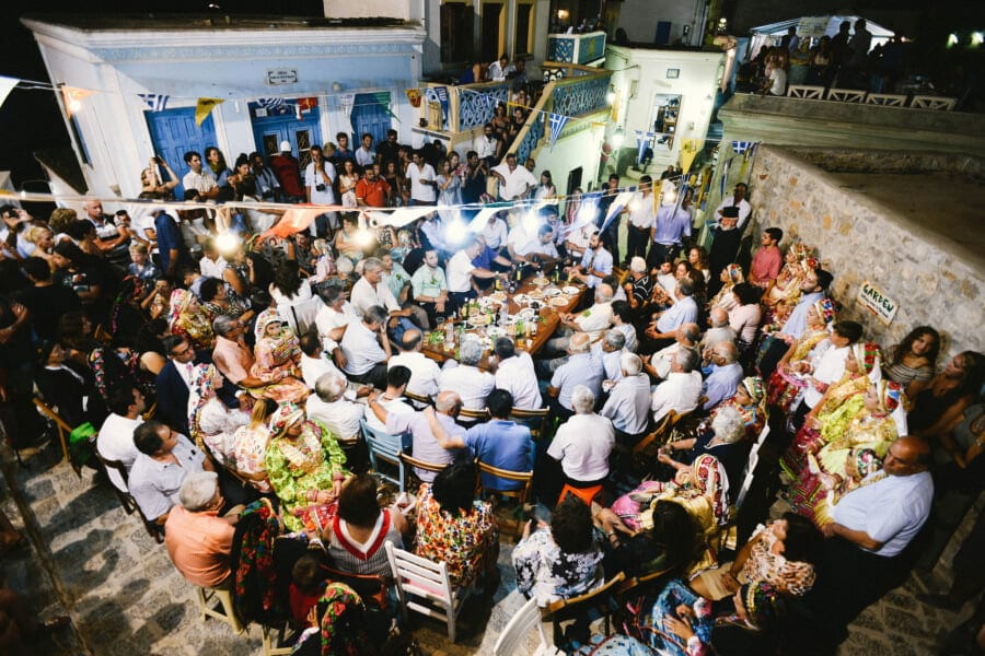 Olympos, Festival of the Assumption of the Virgin Mary - Gastronomy Tours People sitting outside at entrance of the church of the Assumption of Virgin Mary and commemorate festival of her birth at Olympos, Greece